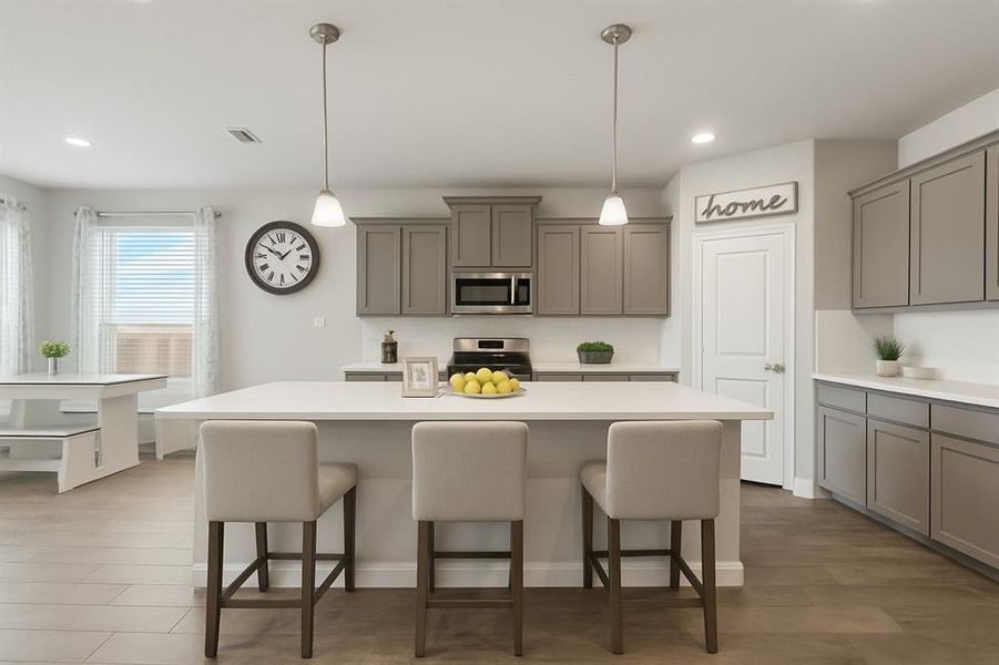 Kitchen with gray cabinets, hanging light fixtures, a breakfast bar area, stainless steel appliances, and a center island