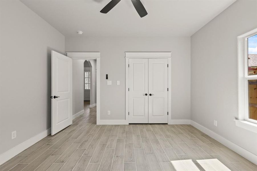 Unfurnished bedroom featuring light wood-style floors, baseboards, and arched walkways