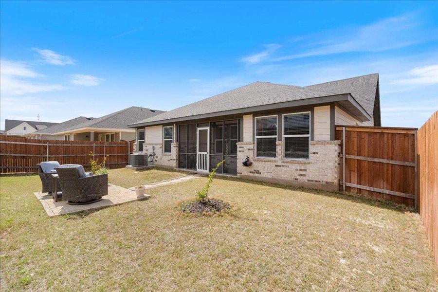 Back of house with a fenced backyard, a lawn, central AC unit, and a patio