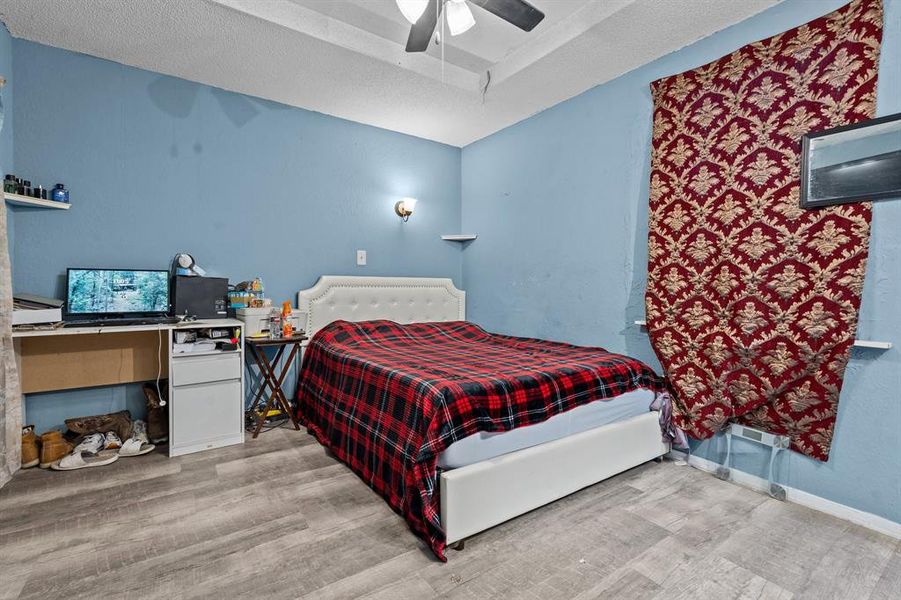 Bedroom featuring ceiling fan, a textured ceiling, and light wood-type flooring