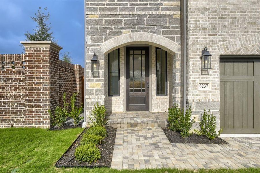 Front entrance featuring an arched portico, a dark wood-finish door with glass inserts, and flanking vertical windows Front entrance featuring an arched portico, a dark wood-finish door with glass inserts, and flanking vertical windows