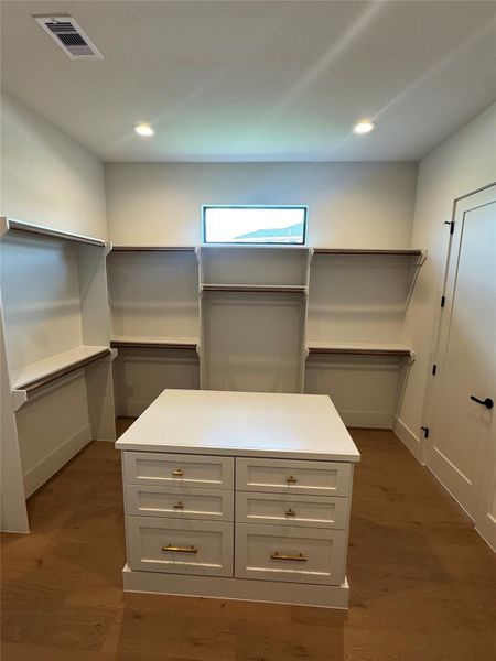 Oversized custom walk-in closet with center island, built-in storage, and extensive hanging space.