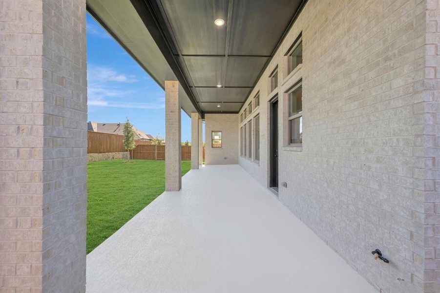 Expansive covered patio with light-toned masonry, recessed lighting, and a neutral concrete surface Expansive covered patio with light-toned masonry, recessed lighting, and a neutral concrete surface