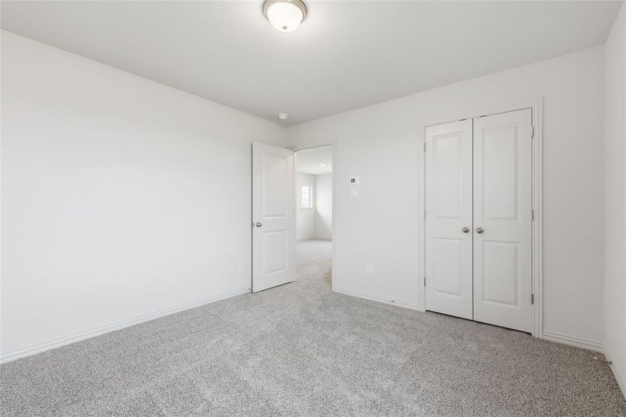 Spacious interior room featuring light-colored walls and grey carpet flooring