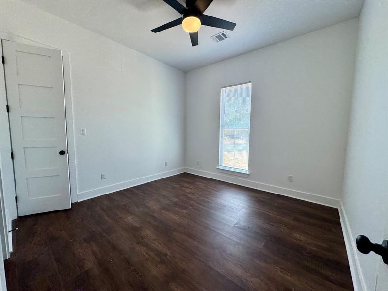 Unfurnished room with dark wood-style floors and a ceiling fan Unfurnished room with dark wood-style floors and a ceiling fan