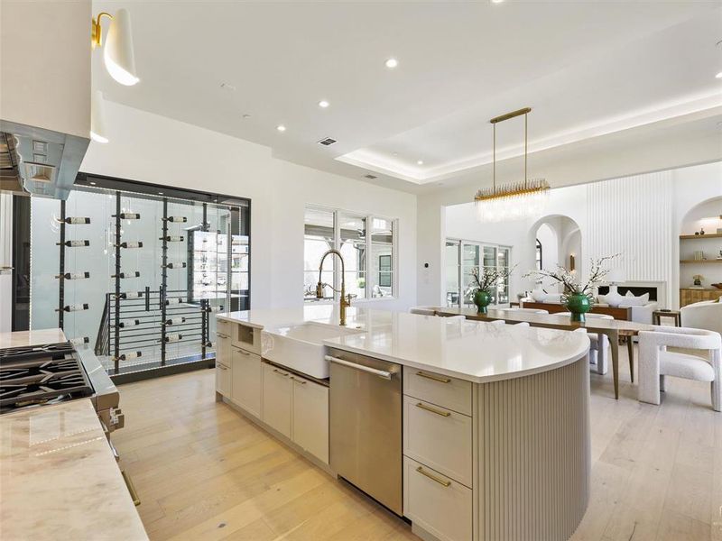 Kitchen with light wood-type flooring, sink, a center island with sink, appliances with stainless steel finishes, and decorative light fixtures