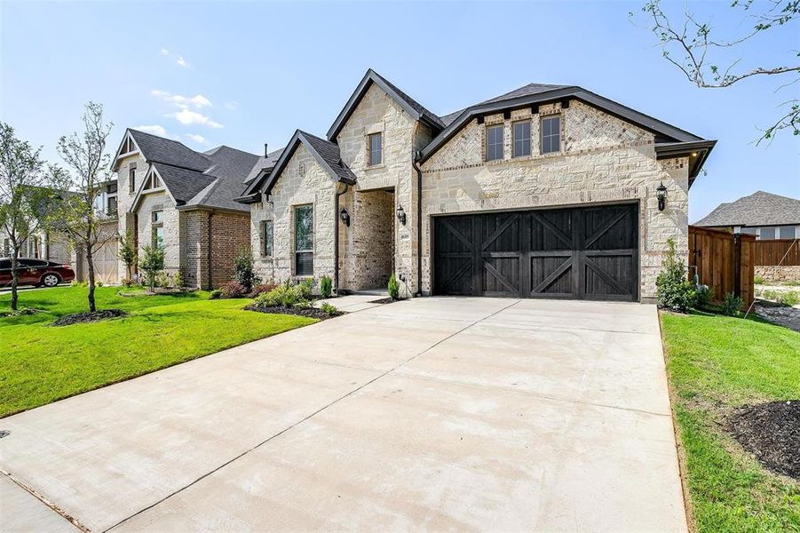 French country style house featuring a front lawn and a garage