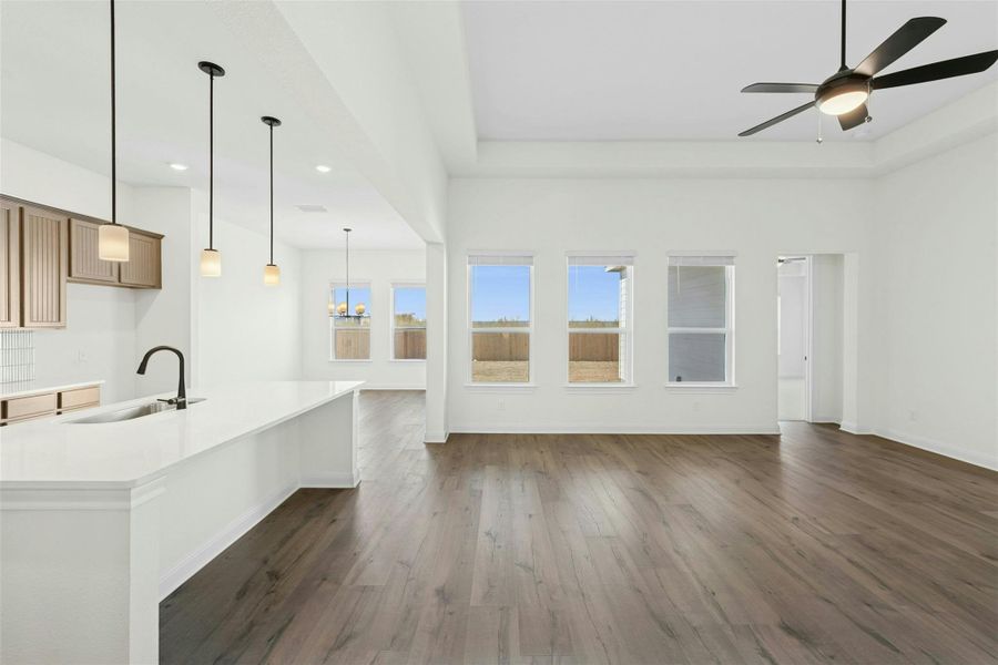 Unfurnished living room featuring hanging lights, dark wood finished floors, and a ceiling fan