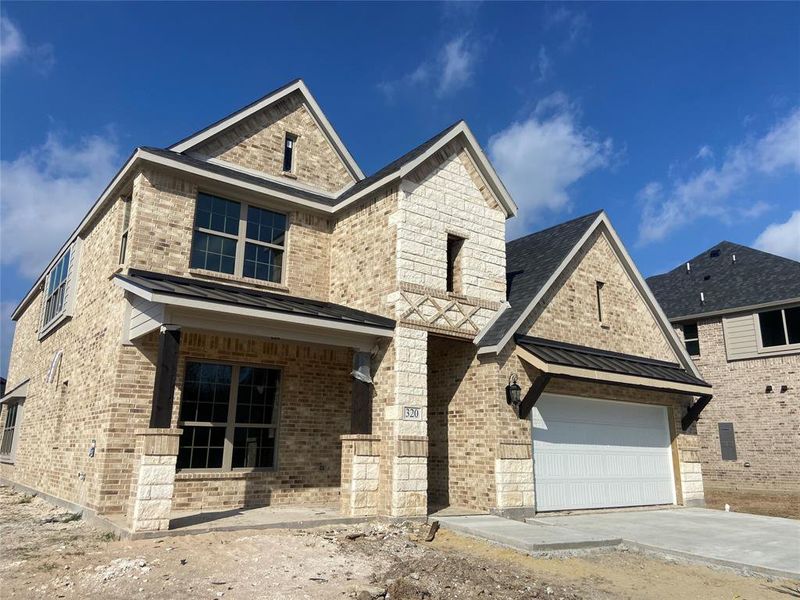 Beautiful stone & brick home with cedar accents and metal front porch roof & accent roof over garage (not painted yet.)