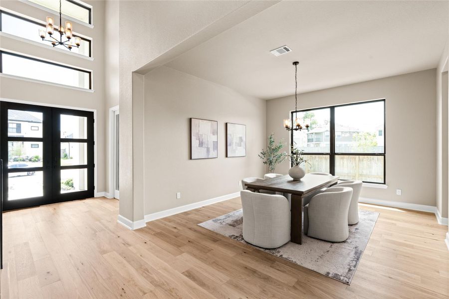 Bright and inviting, this open-concept dining room features large windows, modern light fixtures, and beautiful hardwood floors, perfect for versatile living and entertaining. *Virtually Staged*