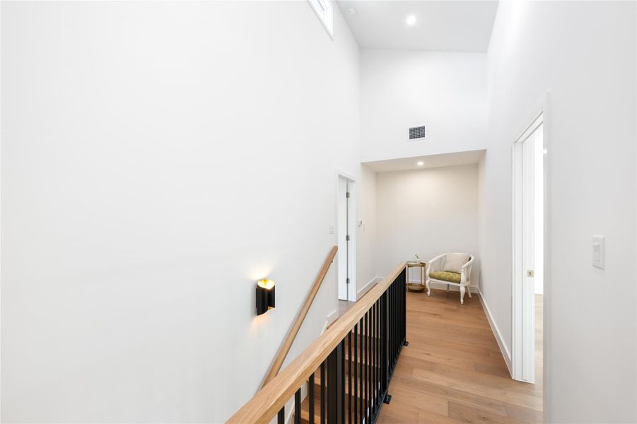 Natural wood flooring complements the high ceilings and recessed lighting in this bright, open hallway. Natural wood flooring complements the high ceilings and recessed lighting in this bright, open hallway.