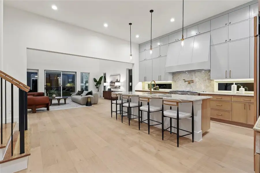Kitchen with a breakfast bar area, open floor plan, a kitchen island with sink, light wood finished floors, and tasteful backsplash