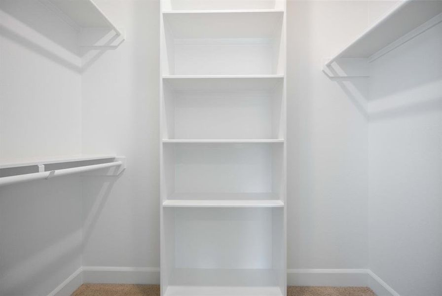 Enjoy the practicality of a walk-in closet with custom shelving in this cozy, secondary bedroom.