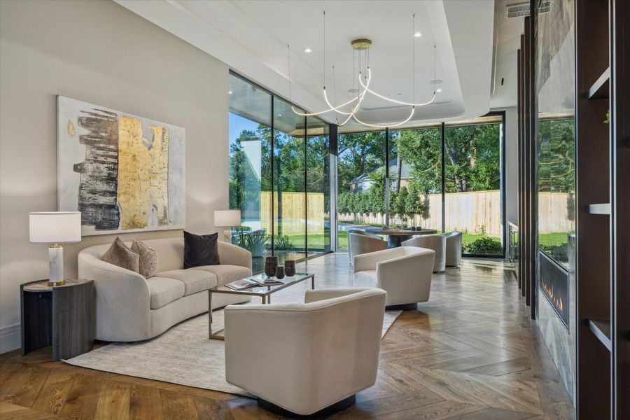 Elegant entertaining area featuring a sleek wet bar with Ocean Fantasy Francini quartzite countertops, custom undermount sink, panel-front beverage fridge and icemaker, and illuminated floating shelves. An adjacent round dining space enjoys seamless flow to the outdoor oasis through walls of glass.