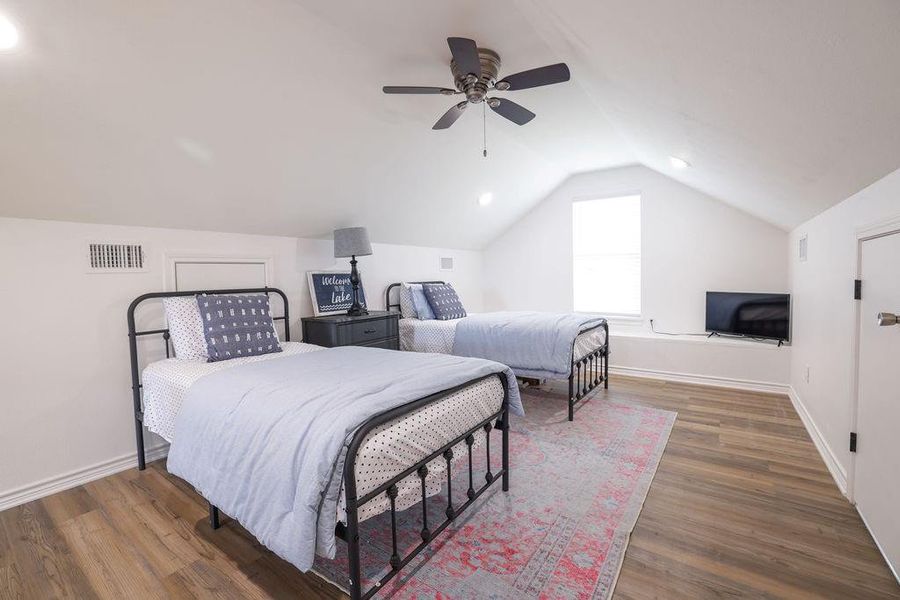 Bedroom with wood finished floors, vaulted ceiling, and a ceiling fan