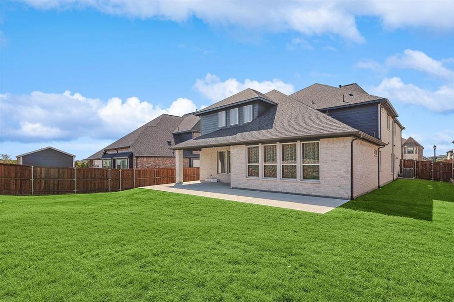 Back of property with central AC, a patio, and a lawn