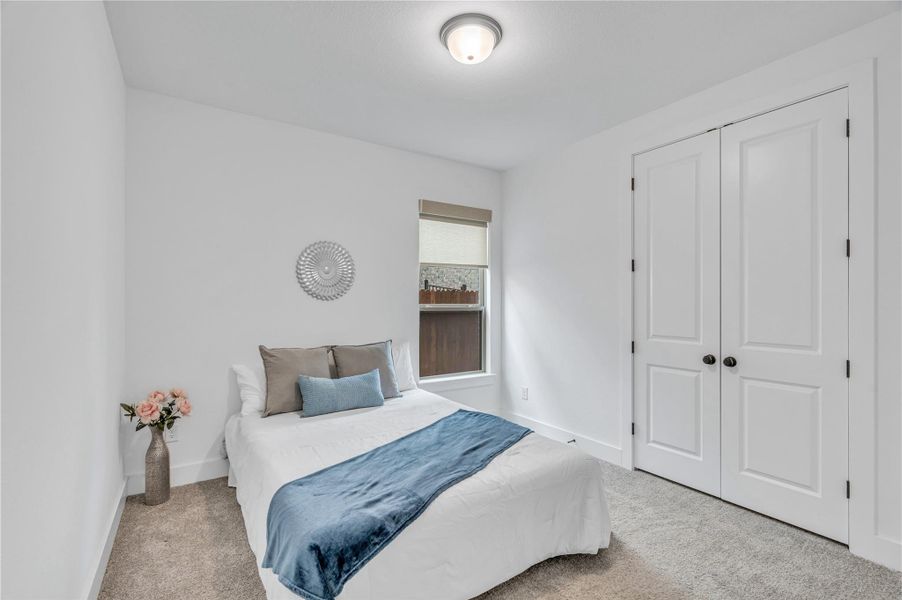 A tranquil bedroom retreat features soft gray carpeting and abundant natural light from a well-placed window.