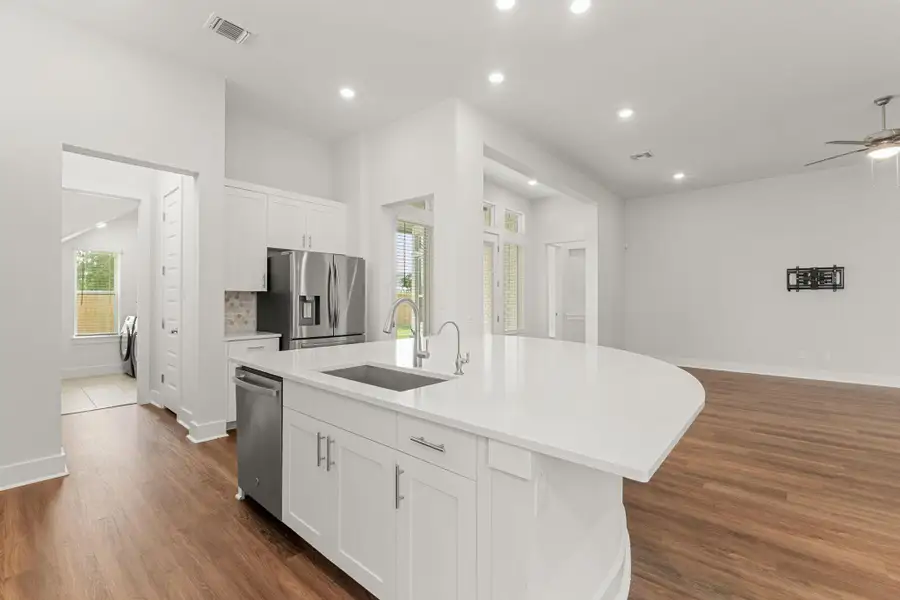 Kitchen featuring appliances with stainless steel finishes, a sink, dark wood finished floors, a center island with sink, and white cabinets Kitchen featuring appliances with stainless steel finishes, a sink, dark wood finished floors, a center island with sink, and white cabinets