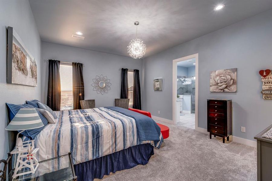 Carpeted bedroom featuring a notable chandelier and ensuite bathroom