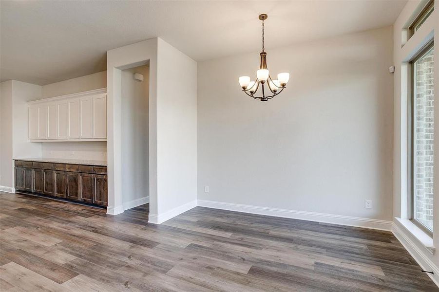 Spare room with light wood-type flooring and a chandelier