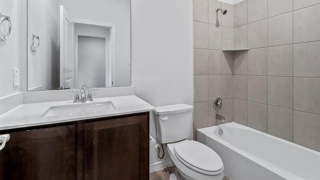 Bathroom featuring a dark wood-finish vanity with a white countertop and integrated sink, a rectangular mirror, and a white toilet