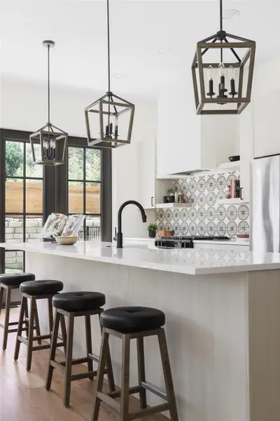 Kitchen featuring modern cabinets, a notable chandelier, light countertops, refrigerator, and white cabinets