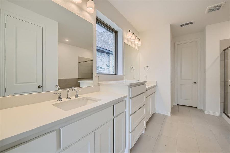 Bathroom featuring vanity with extensive cabinet space, an enclosed shower, and tile flooring