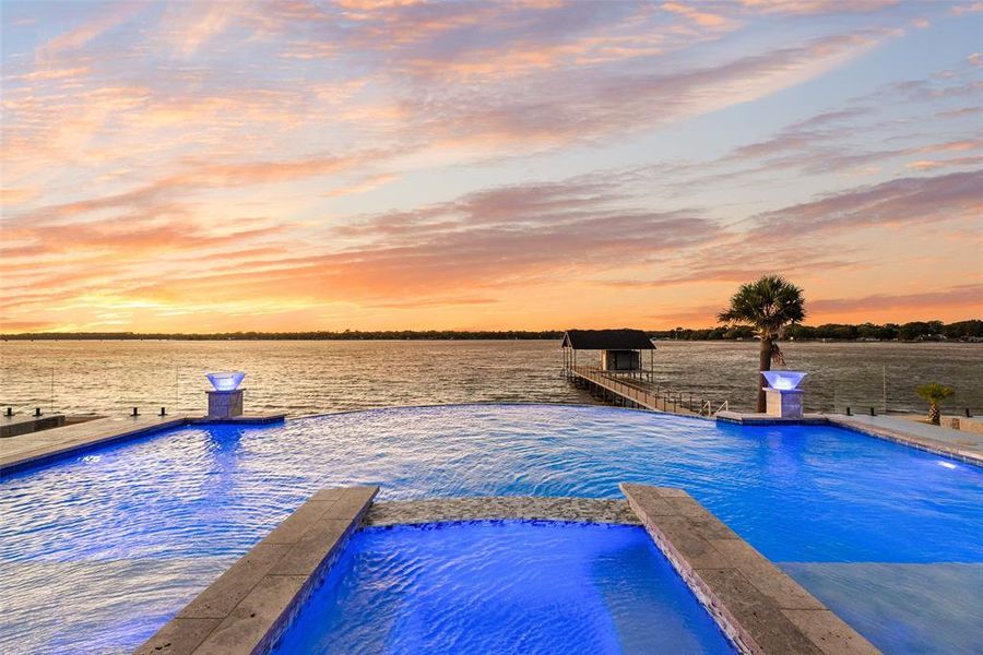 Pool at dusk with a water view and a pool with connected hot tub Pool at dusk with a water view and a pool with connected hot tub