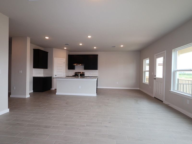 An open-concept living area boasts a modern kitchen with sleek cabinetry and durable tile flooring throughout.