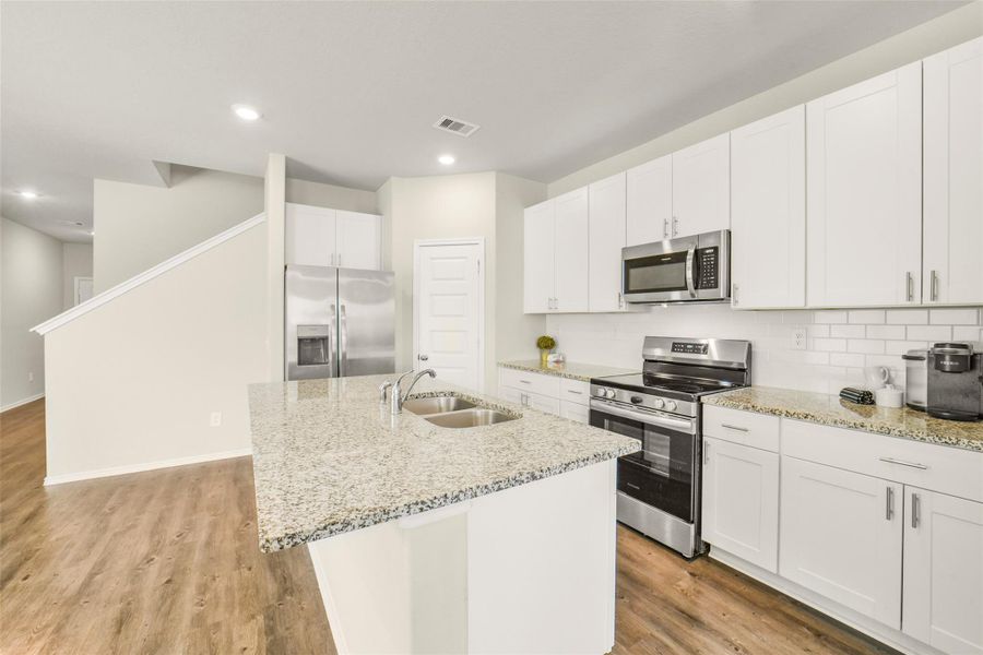 Modern kitchen with granite countertops, stainless steel appliances, and white cabinetry. Features a spacious island with a sink and an open layout. Modern kitchen with granite countertops, stainless steel appliances, and white cabinetry. Features a spacious island with a sink and an open layout.