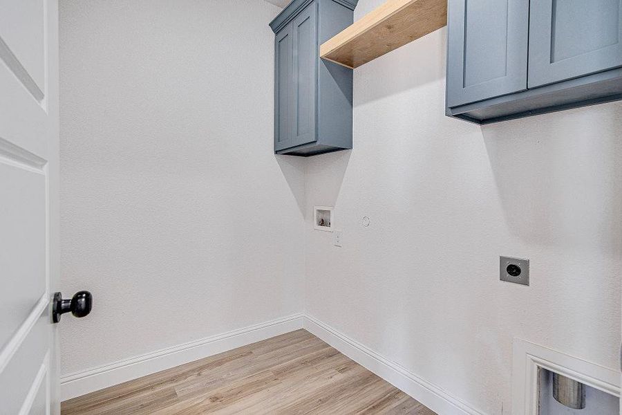 Clothes washing area with cabinet space, electric dryer hookup, baseboards, and washer hookup