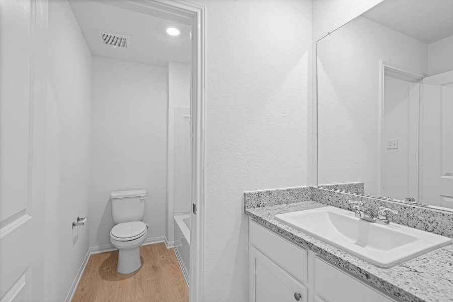 Gleaming stone countertops and a modern vanity frame this thoughtfully arranged bathroom space.
