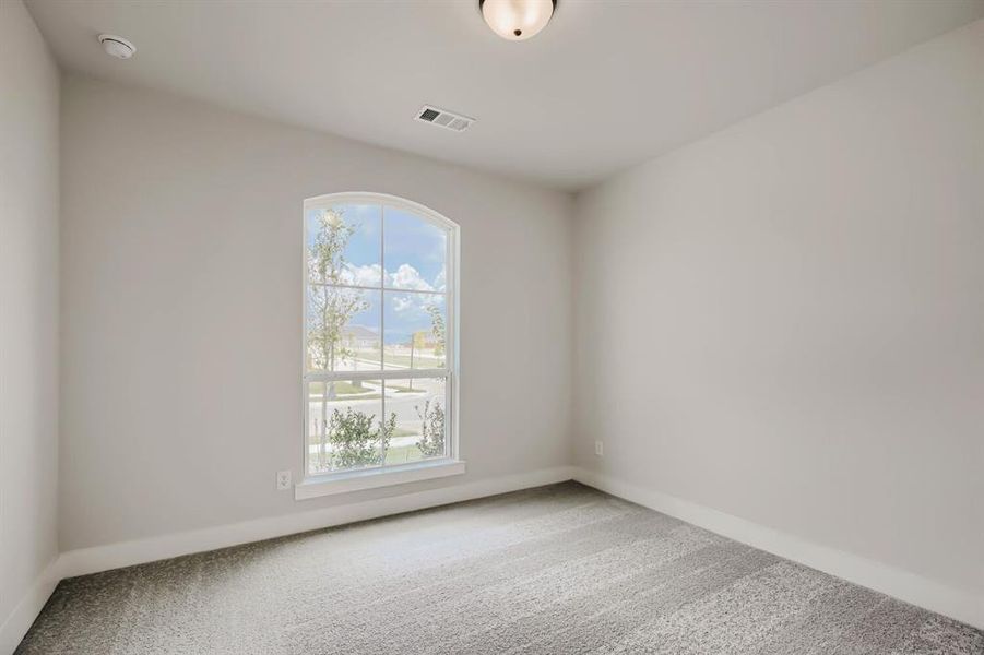 Room featuring a large arched window, light gray walls, gray carpet, white baseboards, and a semi-flush ceiling light fixture
