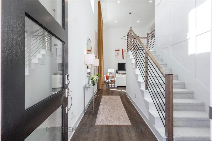 Stairway with wood finished floors, a towering ceiling, and recessed lighting