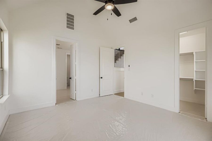 Unfurnished bedroom featuring a spacious closet, ceiling fan, high vaulted ceiling, and finished concrete floors Unfurnished bedroom featuring a spacious closet, ceiling fan, high vaulted ceiling, and finished concrete floors