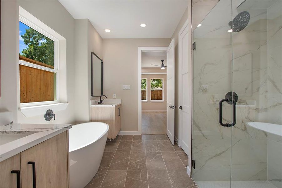 Bathroom featuring independent shower and bath, vanity, and a wealth of natural light