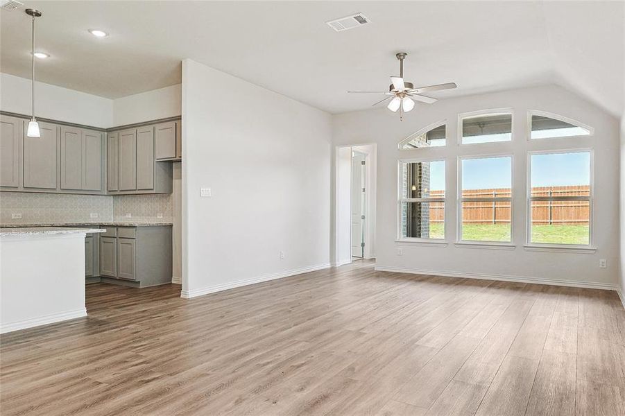 Unfurnished living room featuring vaulted ceiling, light hardwood / wood-style flooring, and ceiling fan