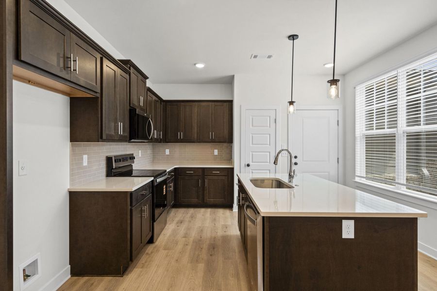 Kitchen featuring dark wood cabinetry, light-toned countertops, and wood-finish flooring