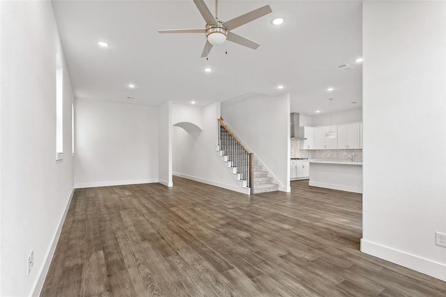 Unfurnished living room featuring ceiling fan and dark wood-type flooring