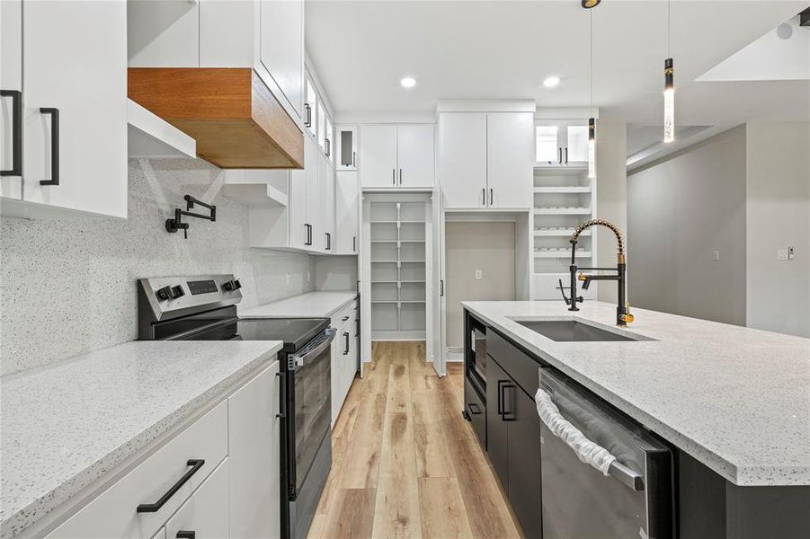 Kitchen featuring white cabinetry, stainless steel appliances, pendant lighting, light stone counters, and recessed lighting