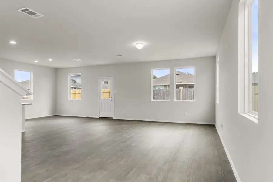 Image of a two story home living room with brown flooring and grey walls with windows