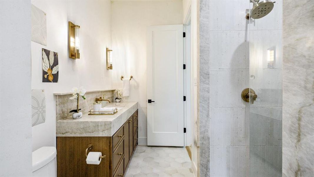 Bathroom featuring vanity, tile patterned flooring, toilet, and a shower