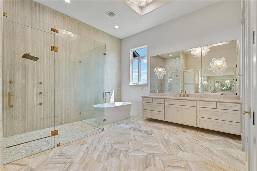 Bathroom with a chandelier, a freestanding tub, a stall shower, and vanity
