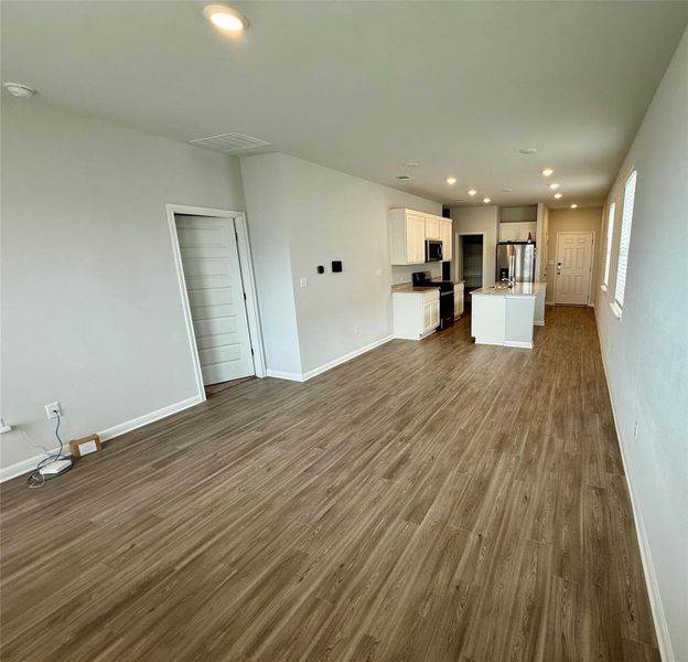 Open-concept living area featuring wood-finish flooring, recessed lighting, and crisp white baseboards