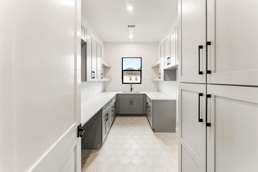 Spacious second-floor utility room provides practicality and efficiency with a large sink, abundant cabinet storage, and generous counter space for folding and organizing.