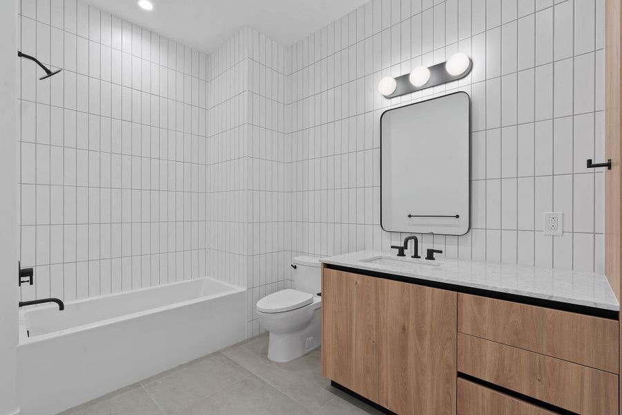 Full bath with tile walls, light tile patterned flooring, vanity,  shower combination, and recessed lighting