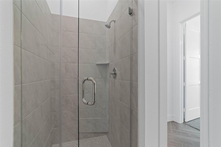 View of the secondary bathroom walk-in shower with tile surround and glass frame.