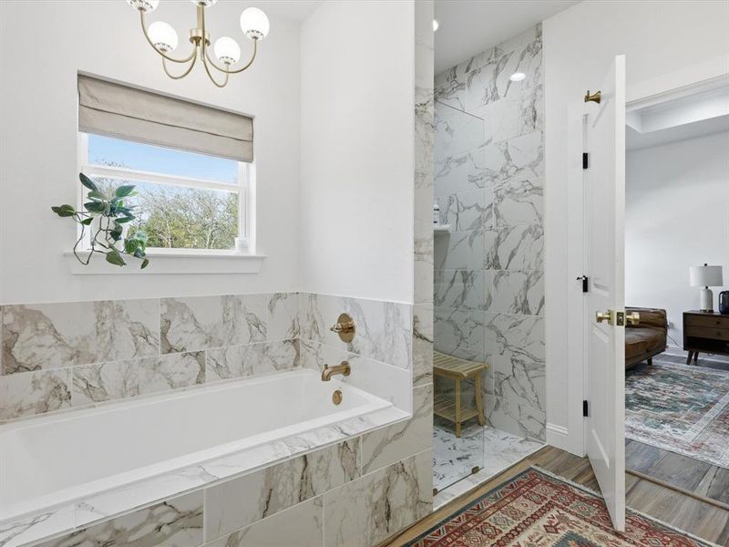 Bathroom with a garden tub, a marble finish shower, a chandelier, wood finished floors, and connected bathroom