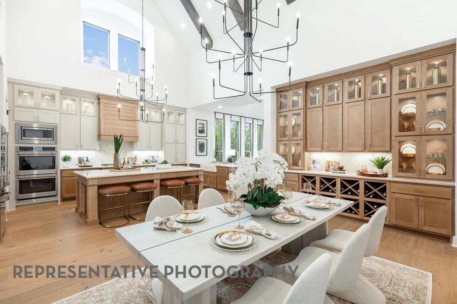 Dining area featuring a towering ceiling, a notable chandelier, and light wood-type flooring