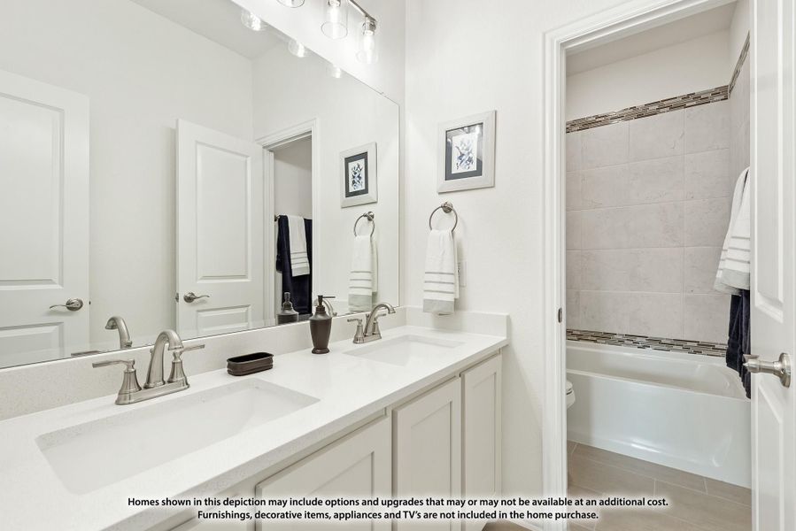 Bathroom with double sink vanity, large mirror, and tiled bathtub-shower combo with mosaic accent border Bathroom with double sink vanity, large mirror, and tiled bathtub-shower combo with mosaic accent border